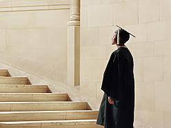 a person in a graduation gown and cap walking up stairs