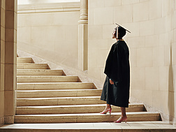 a person in a graduation gown and cap walking up stairs