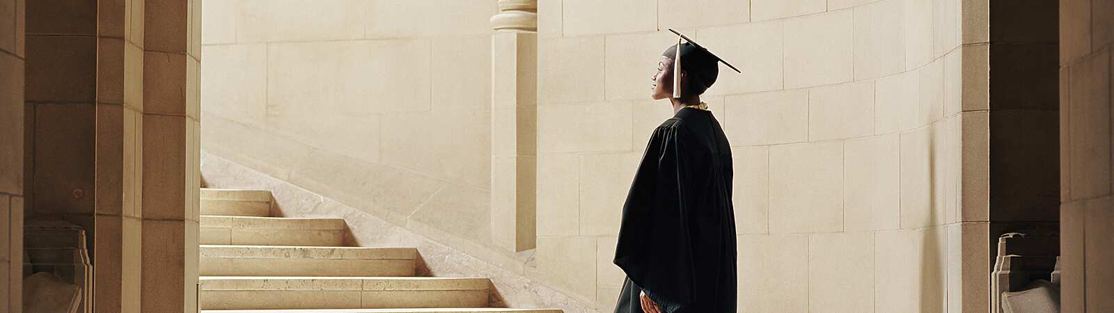 a person in a graduation gown and cap walking up stairs