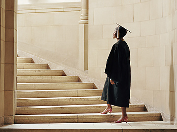 a person in a graduation gown and cap walking up stairs