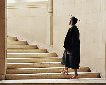 a person in a graduation gown and cap walking up stairs