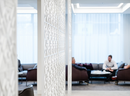 a room with a white screen and people sitting on the couch