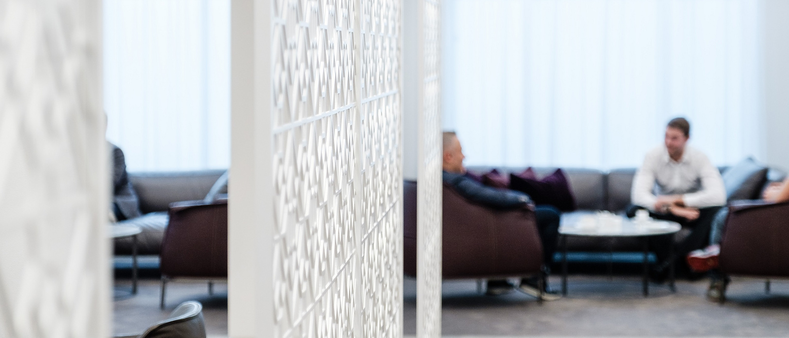 a room with a white screen and people sitting on the couch