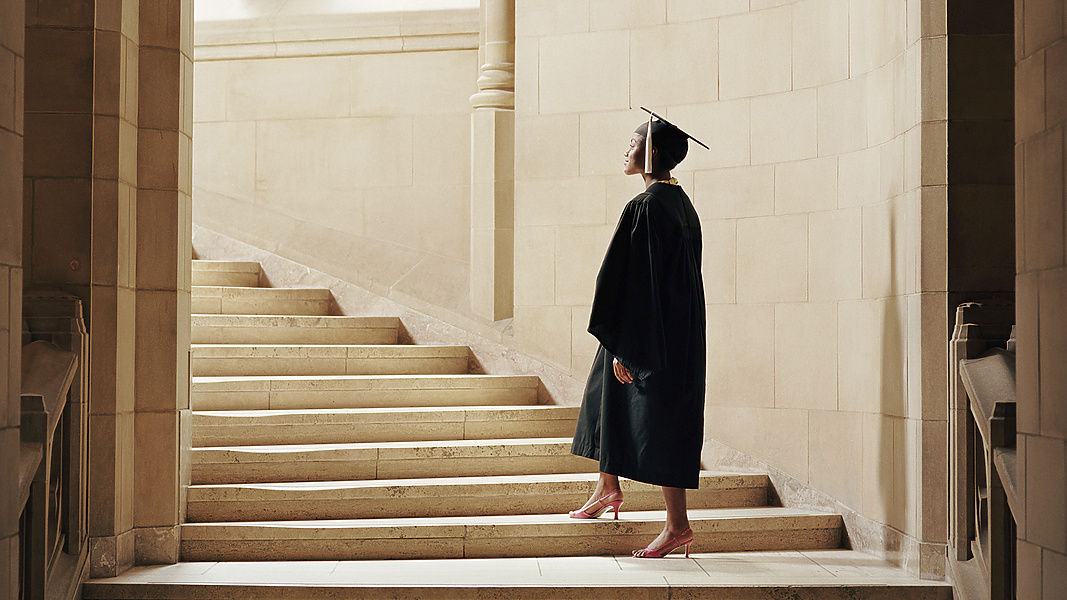 a person in a graduation gown and cap walking up stairs