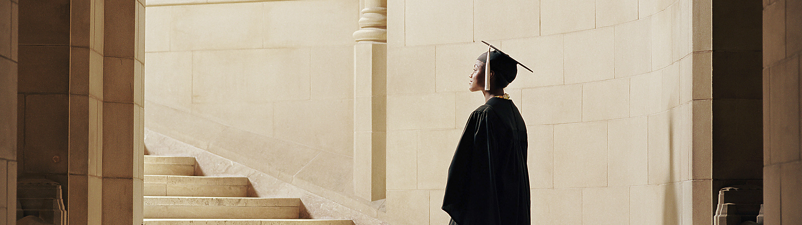 a person in a graduation gown and cap walking up stairs