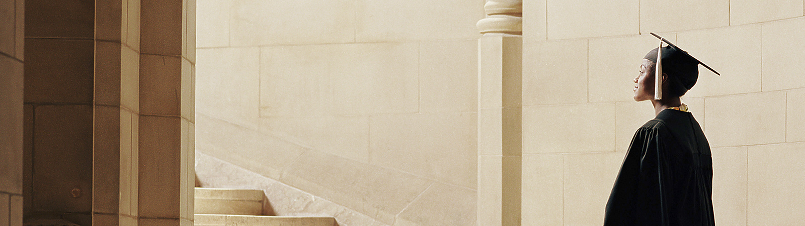 a person in a graduation gown and cap walking up stairs