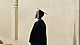 a person in a graduation gown and cap walking up stairs