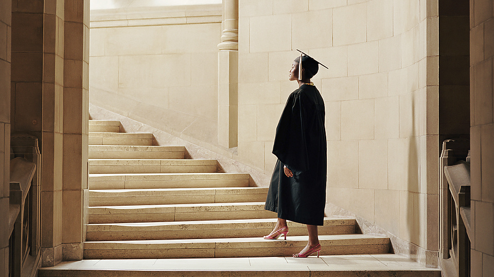 a person in a graduation gown and cap walking up stairs
