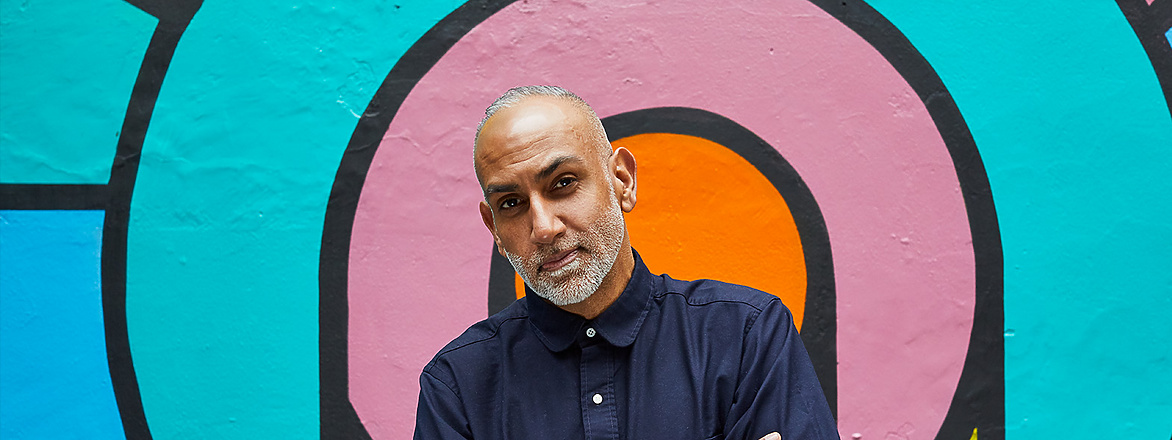 a person standing in front of a colorful wall