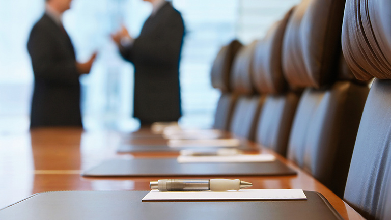 a pen on a table in a conference room with people talking in the background