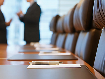a pen on a table in a conference room with people talking in the background
