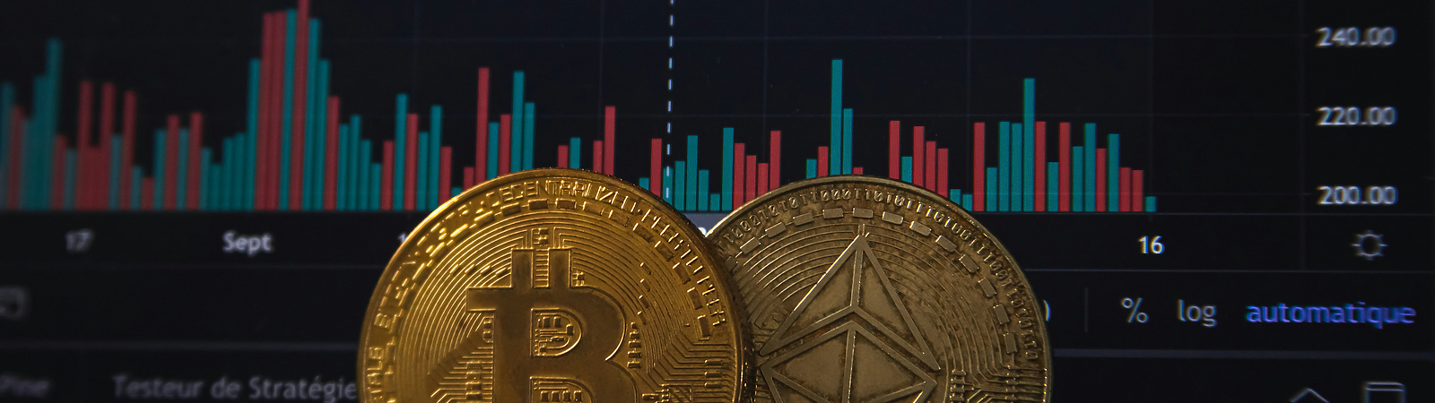 lose-up of physical Bitcoin and Ethereum coins placed in front of a computer screen displaying cryptocurrency price charts and trading data