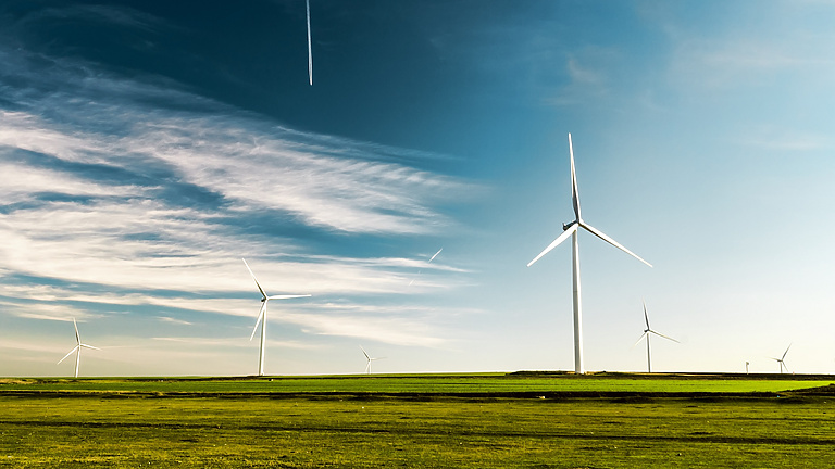 Wind turbines in field under blue sky