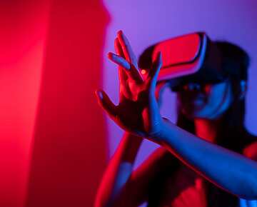 Young woman using glasses of virtual reality on dark background. Smartphone using with VR headset,virtual reality,future technology concept.