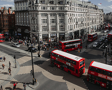 a group of people walking on a street with buses and people