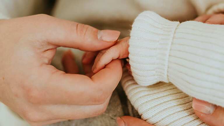 A person holding a baby's hand