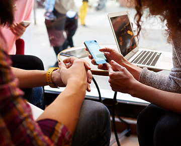Two people in public space looking at mobile device