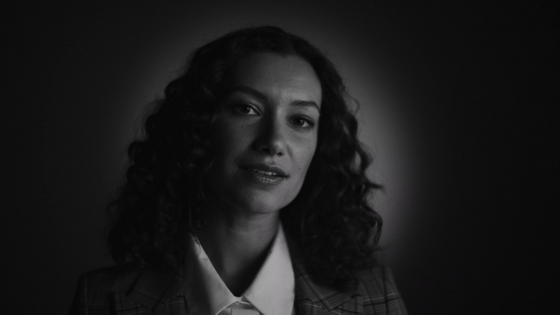 a person with curly hair wearing a suit