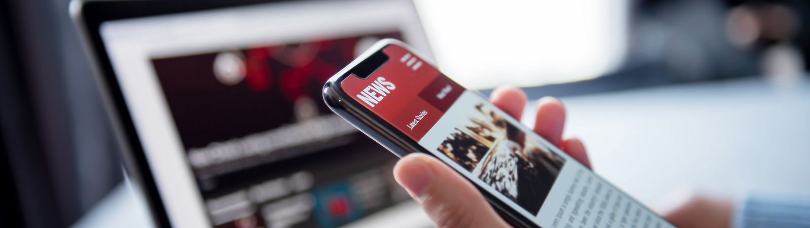 a person holding a phone in front of a laptop