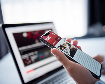 a person holding a phone in front of a laptop