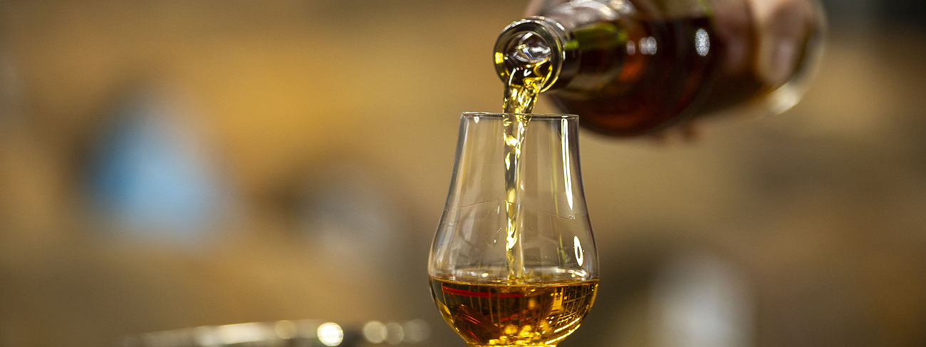 person pouring whiskey in an whiskey glass
