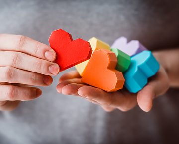 Person holding multicoloured love hearts