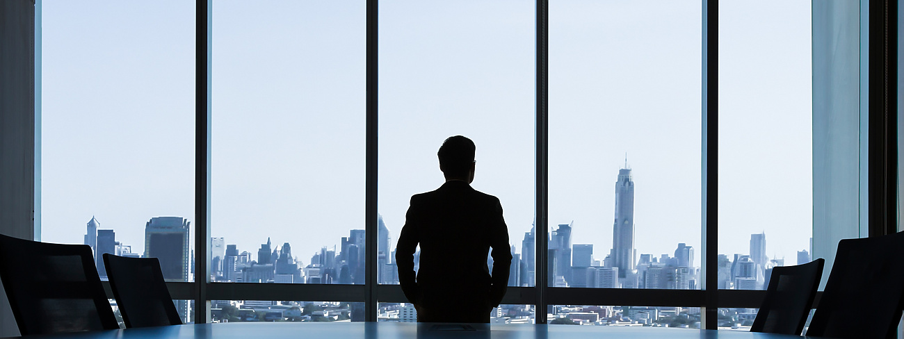 man looking out of window of corporate office