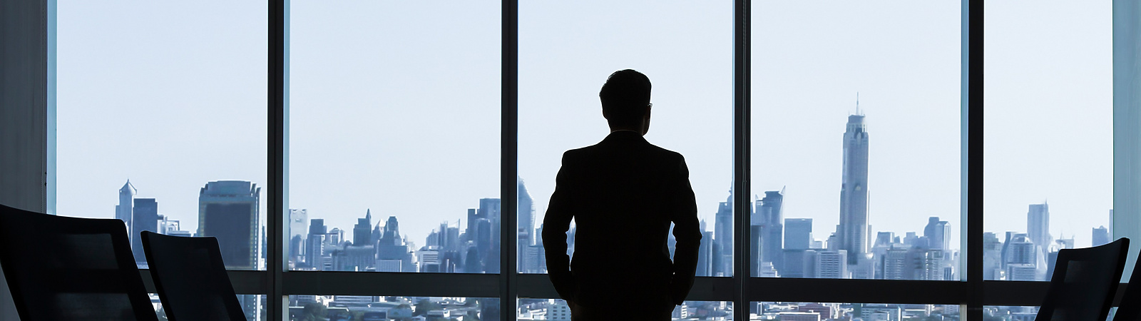 man looking out of window of corporate office