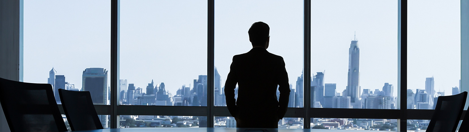 man looking out of window of corporate office