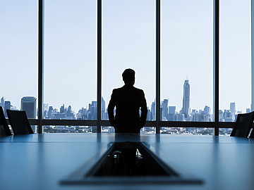 man looking out of window of corporate office