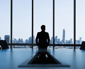 man looking out of window of corporate office