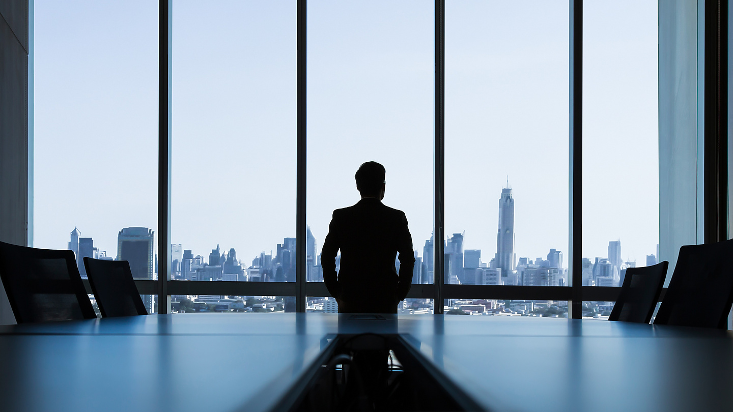 man looking out of window of corporate office
