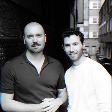 Two men standing together in a narrow alleyway