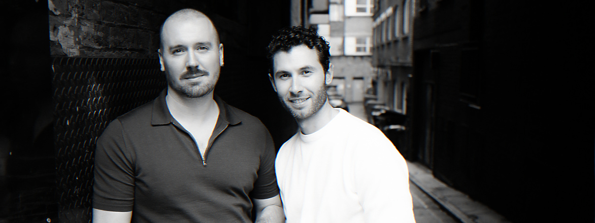 Two men standing together in a narrow alleyway