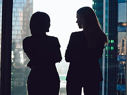 two women talking by window in corporate office