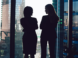 two women talking by window in corporate office