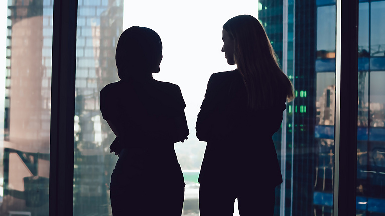 two women talking by window in corporate office