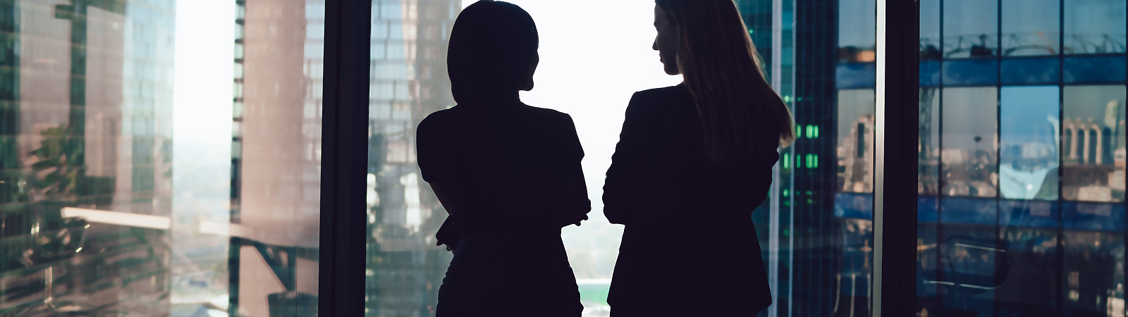two women talking by window in corporate office