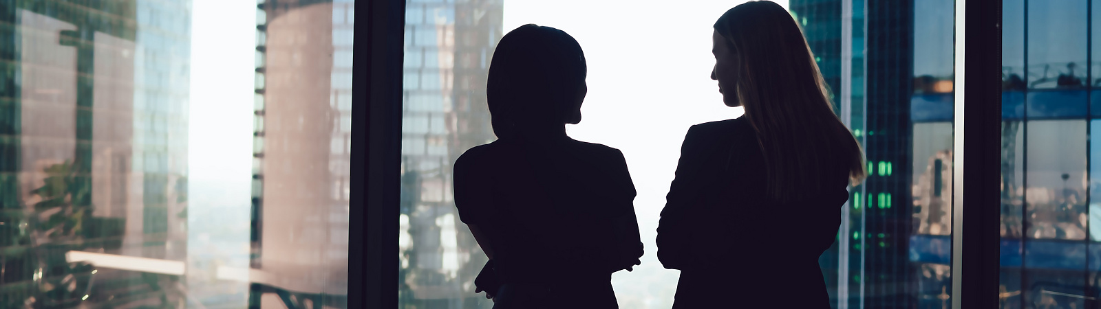 two women talking by window in corporate office