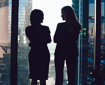 two women talking by window in corporate office