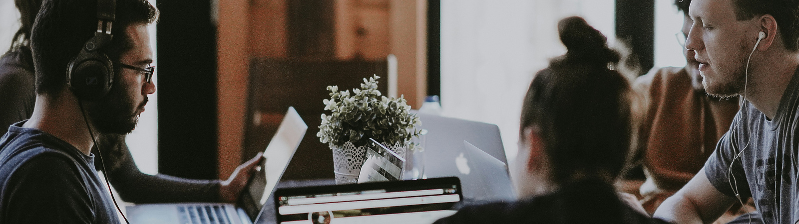 a group of people sitting around a table with laptops