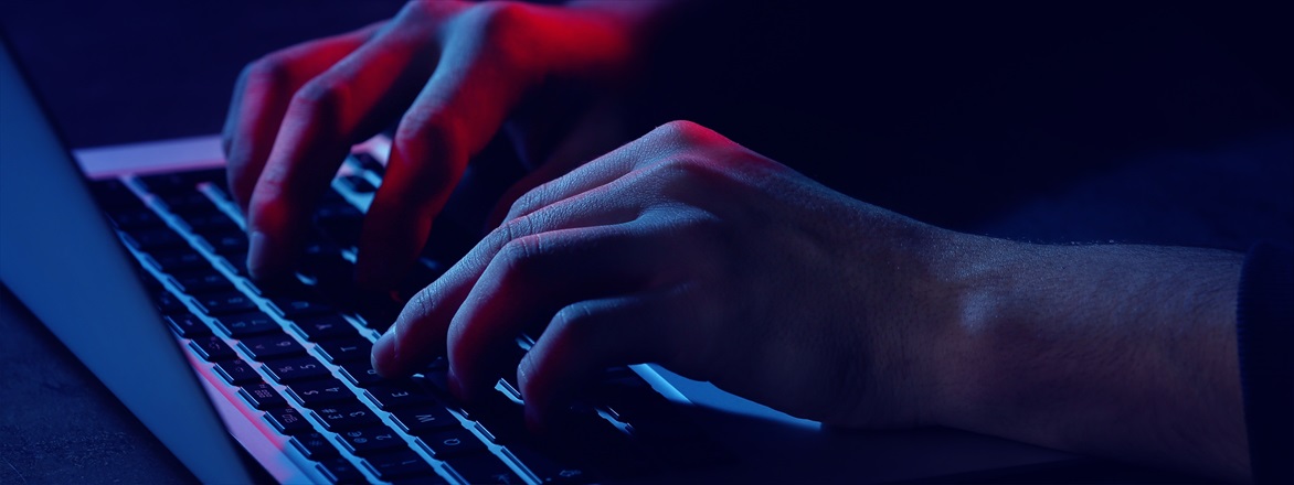 Person's hands on laptop in dark room