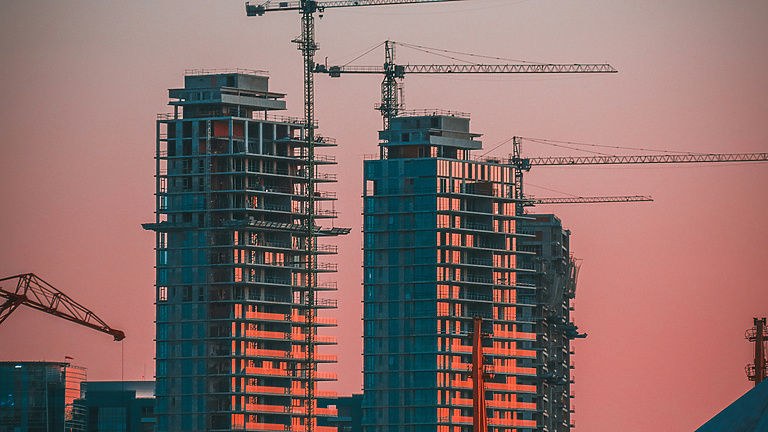 sunset over construction site with cranes in the background