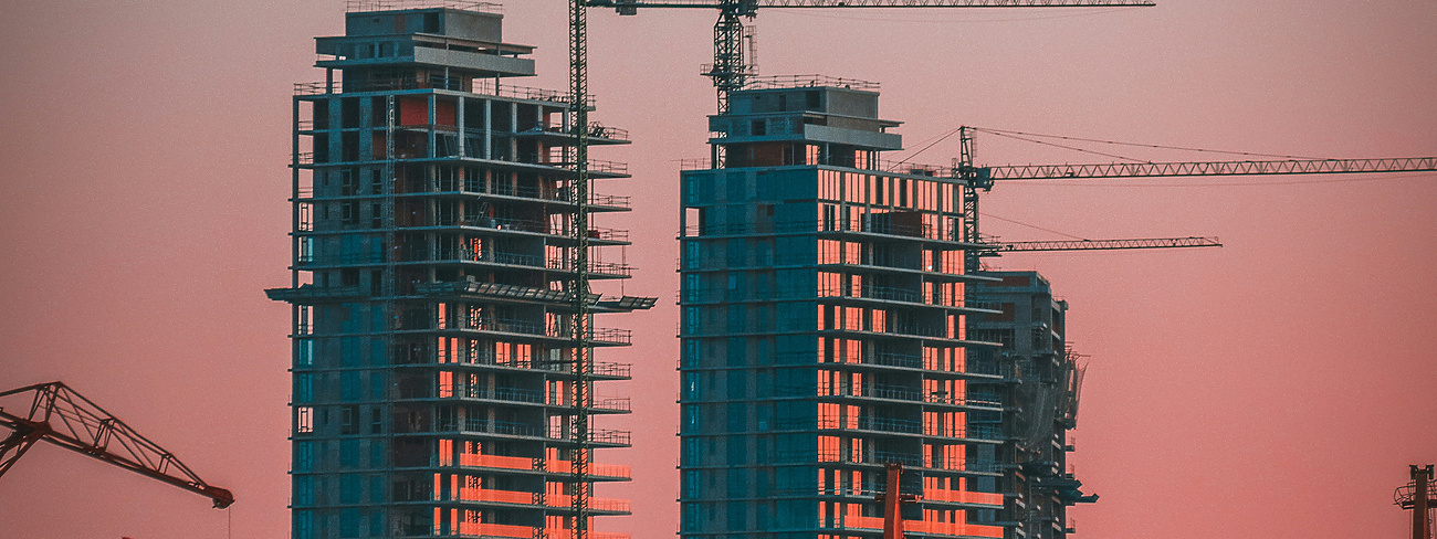 sunset over construction site with cranes in the background