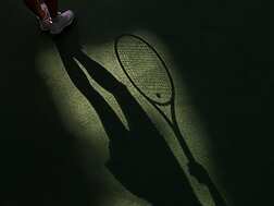 a shadow of a tennis player holding a racket