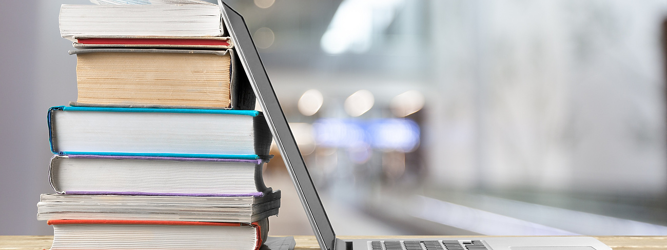 Books stacked next to laptop on desk