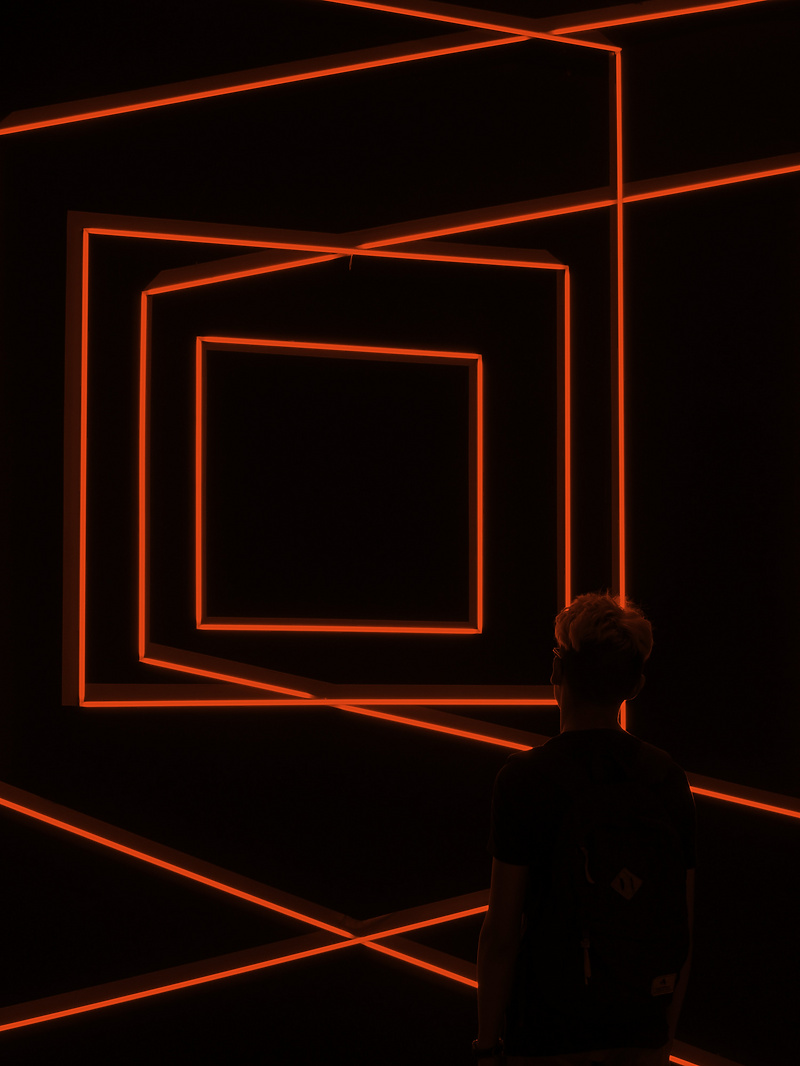 a person standing in front of a black wall with orange lights