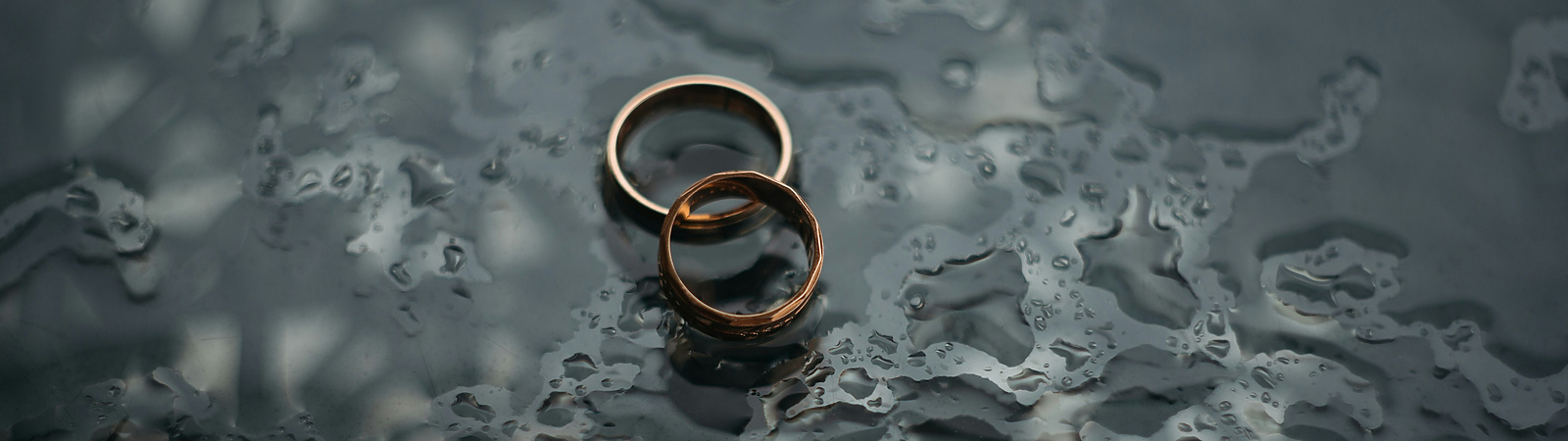 a pair of gold rings on a wet surface