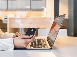 a person holding a credit card and using a laptop