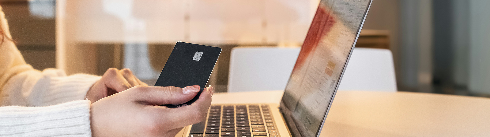 a person holding a credit card and using a laptop